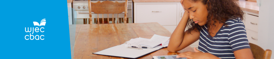 Learner at a table studying with a hand pressed against head.