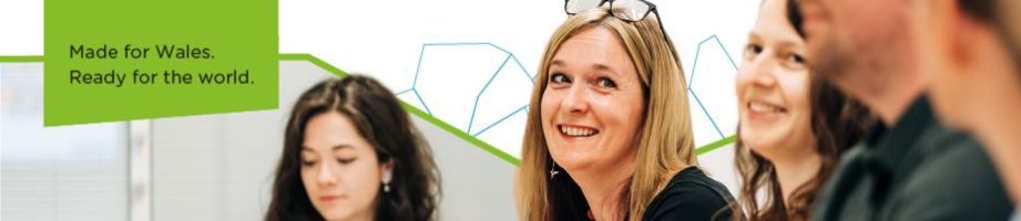 Smiling staff with geometric shape outlines in the background and text: Made for Wales.
