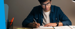 Learner studying at a desk with a dim light.